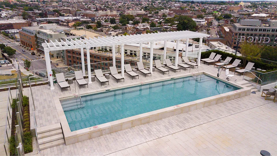 Custom rooftop fiberglass pergola shading lounge chairs by the pool.